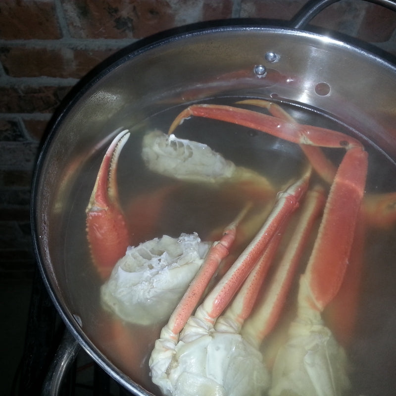 Snow crab boil spread on a table with crab legs, shrimp, corn, sausage, and potatoes seasoned with Old Bay