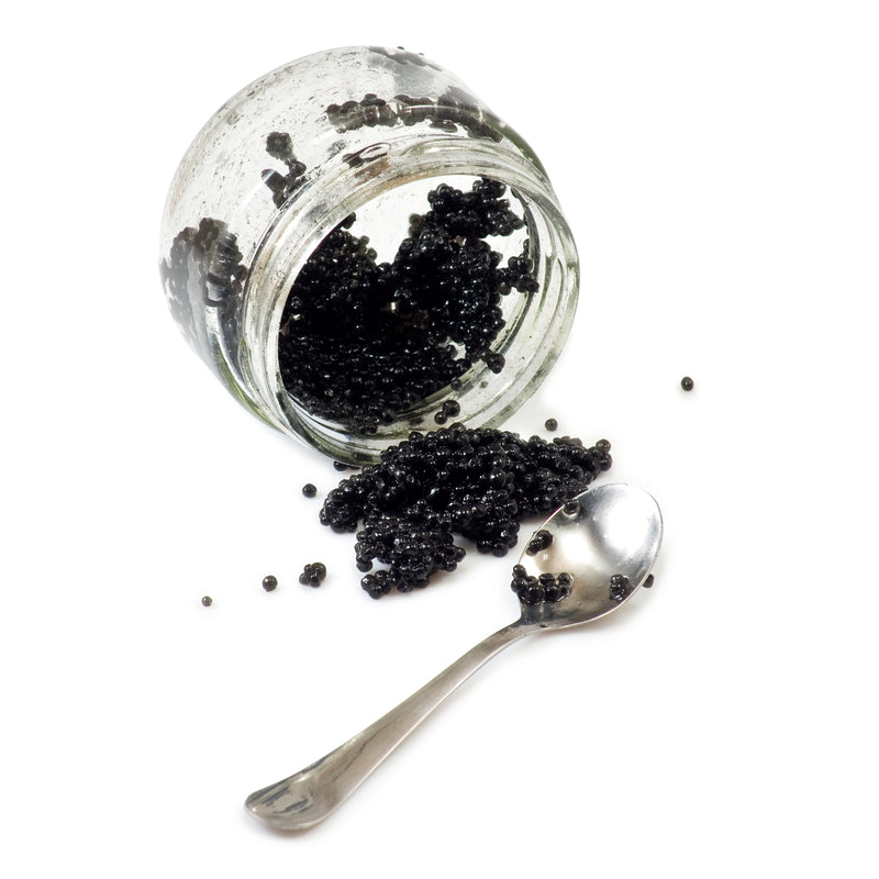 Five elegant caviar appetizers including blinis, deviled eggs, potato bites, smoked salmon crostini, and tarts arranged on a dark slate board