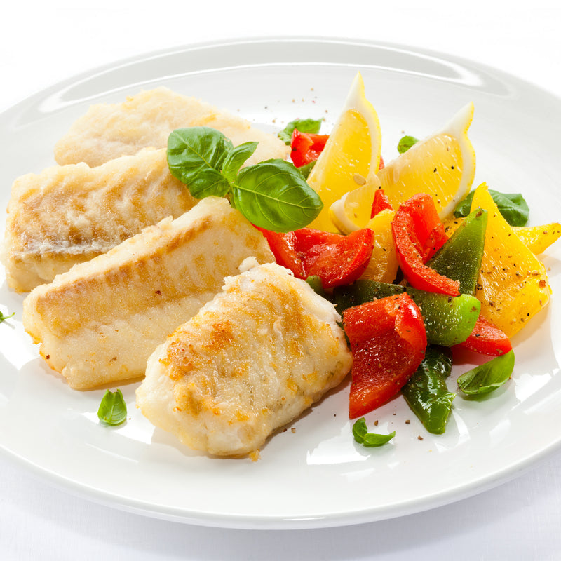 Grilled lingcod fillet with lemon and fresh herbs on a plate