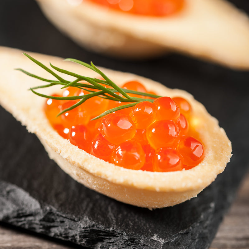 Golden crispy Ikura fritters on a white plate garnished with green onions and sesame seeds, served with soy dipping sauce