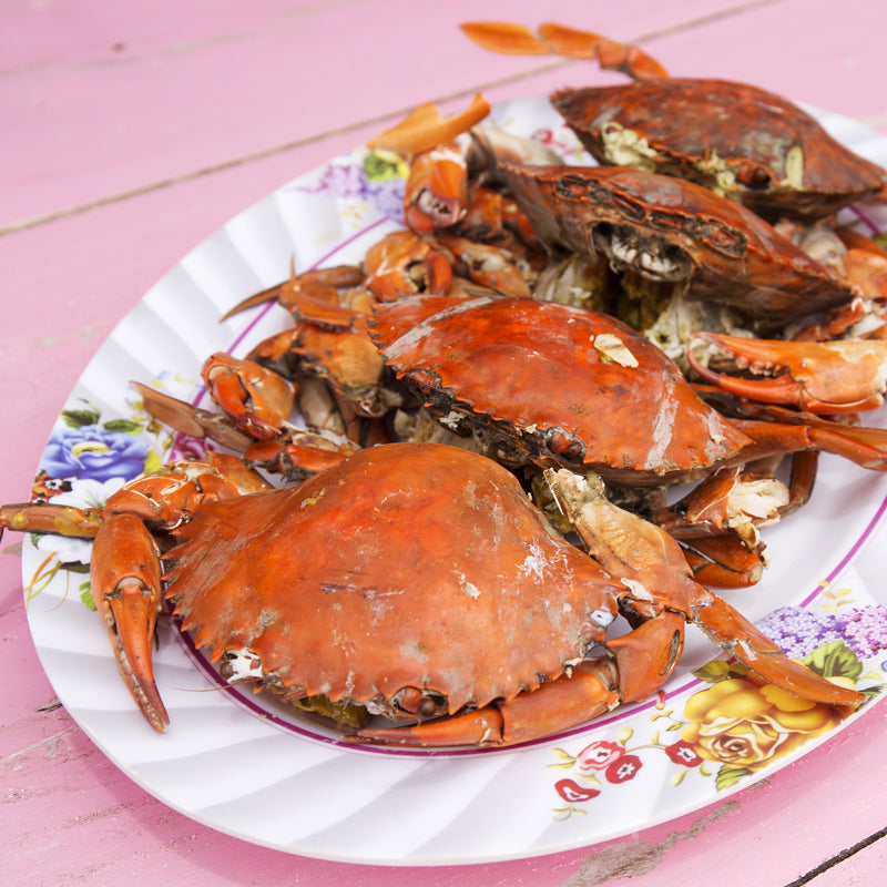 Freshly cooked red king crab legs served with garlic butter, lemon wedges, and herbs on a wooden board