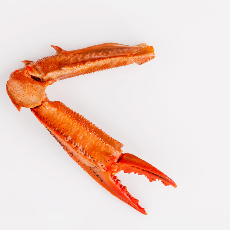 Deep-sea red crab claws arranged on a platter with lemon wedges and cocktail sauce, showcasing their vibrant color and tender meat