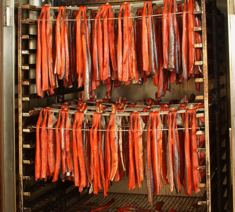 Freshly smoked salmon fillet with alder wood chips and herbs on a smoker rack