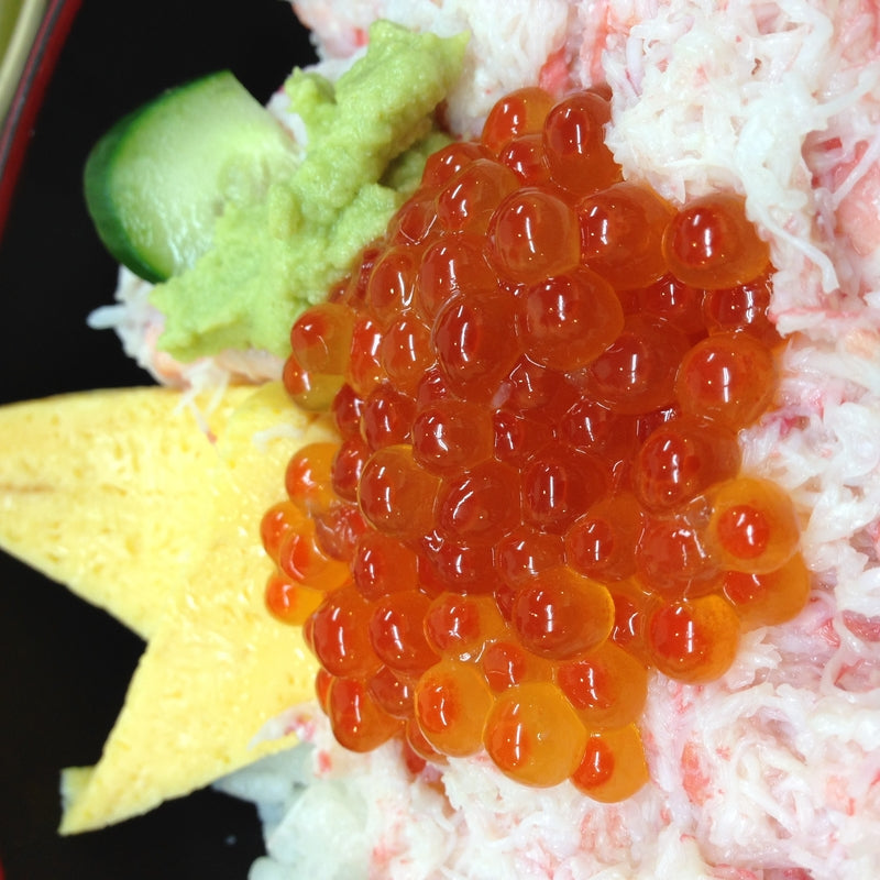 Vibrant orange-red ikura salmon roe served in a small dish, glistening and fresh