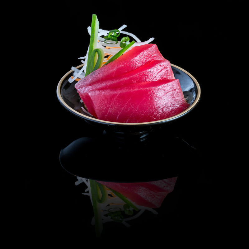 Smoked tuna sushi pizza on a wooden board — a crispy golden sushi rice crust topped with creamy avocado, thinly sliced smoked tuna, cucumber, radish, sesame seeds, and a drizzle of spicy mayo