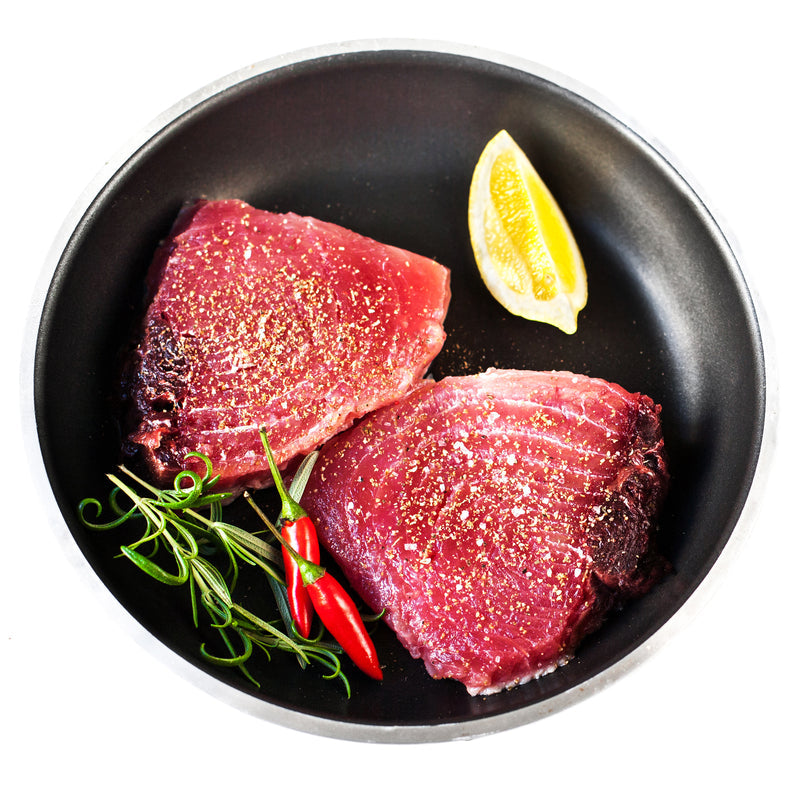 Smoked ahi tuna steak on a wooden board with citrus salsa, fresh herbs, and a side of toasted baguette crostini