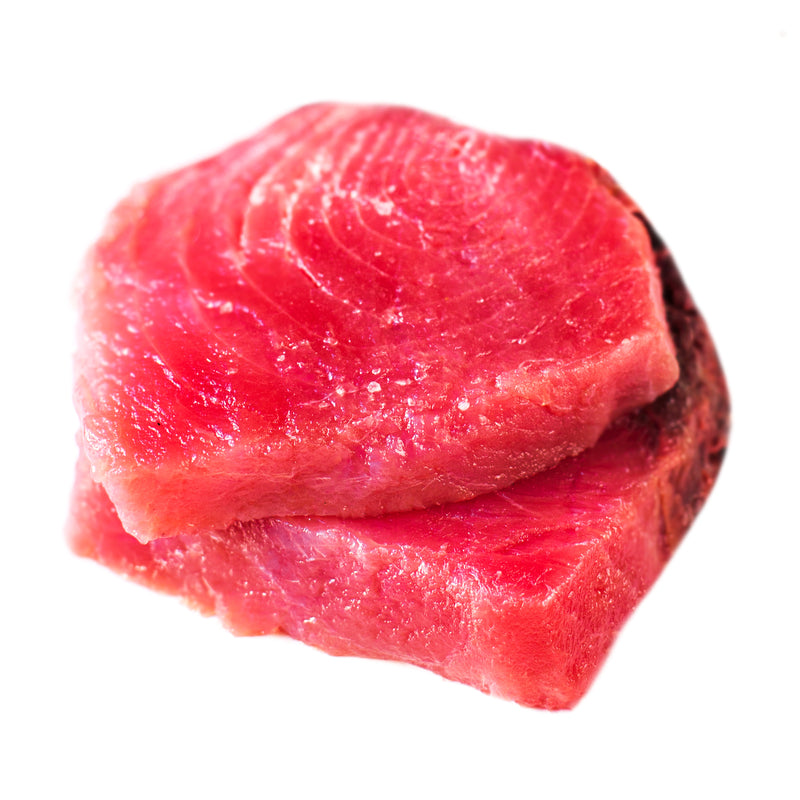 Smoked albacore tuna fillet on a wooden board with fresh herbs, lemon wedges, and a side of sushi rice and avocado