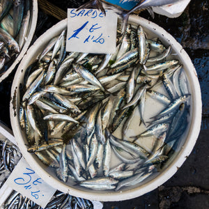 A flavorful arrangement of Portuguese grilled sardines garnished with lemon and herbs, accompanied by a side of fresh salad and crusty bread, showcasing the simplicity and elegance of sardine dishes