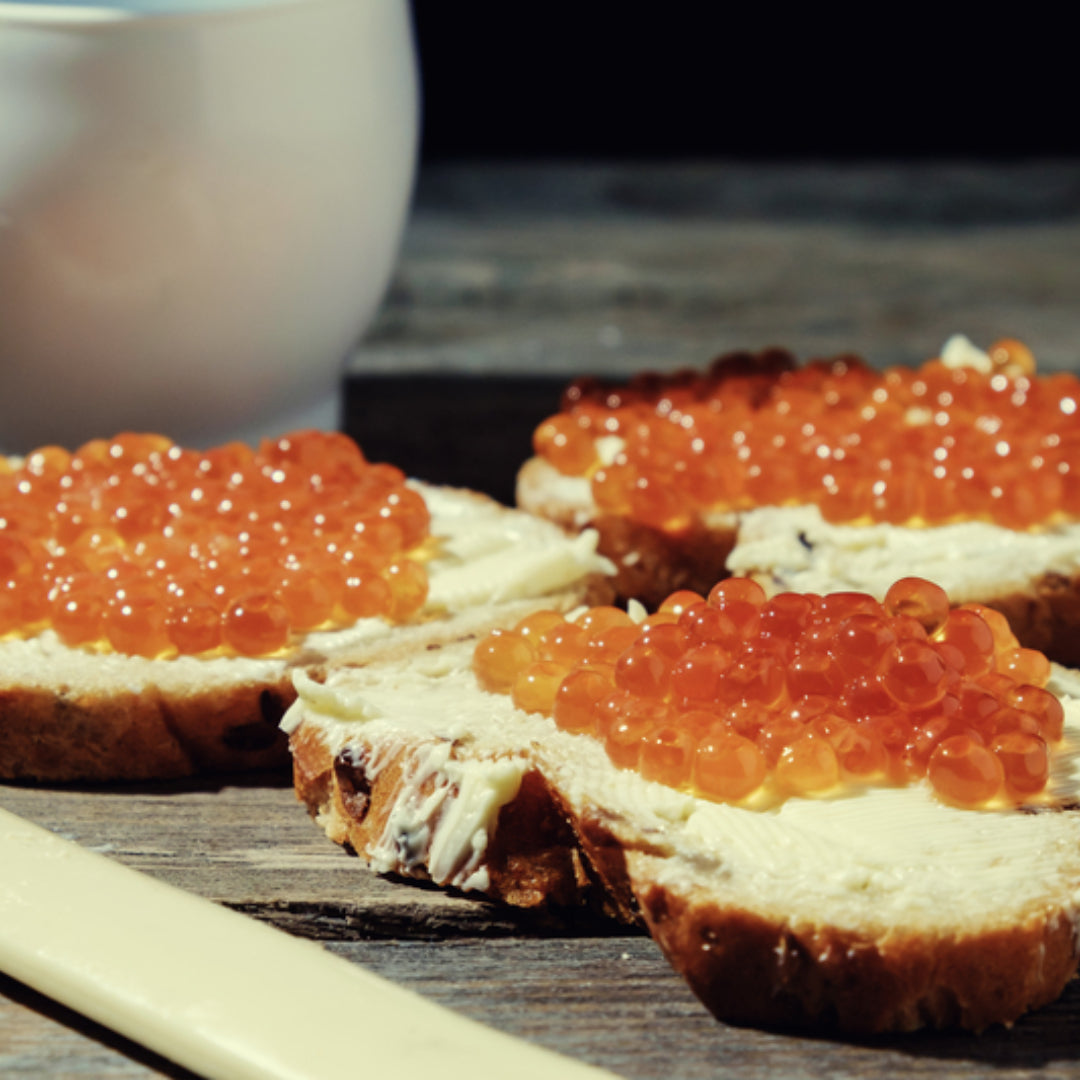 Glistening salmon roe ikura served over sushi rice with nori and chopsticks