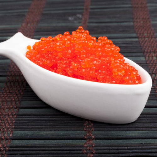 Salmon roe nigiri pieces topped with vibrant orange ikura on a wooden sushi board
