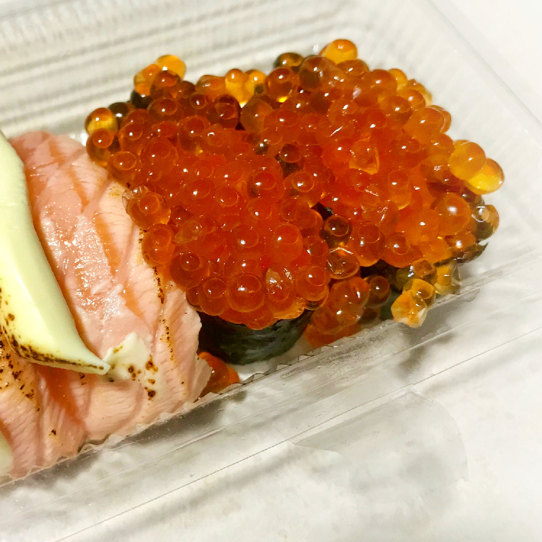 Gourmet ikura sandwich on toasted sourdough with vibrant orange salmon roe, sliced avocado, cucumber, and fresh dill on a wooden board