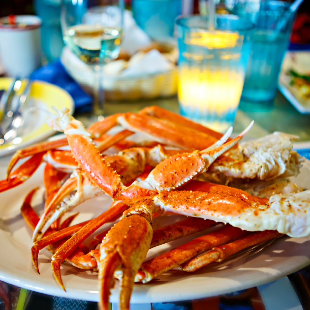 A platter of premium crab claws including Alaskan king crab, Jonah crab, and cocktail crab claws arranged on ice with lemon wedges and dipping sauces