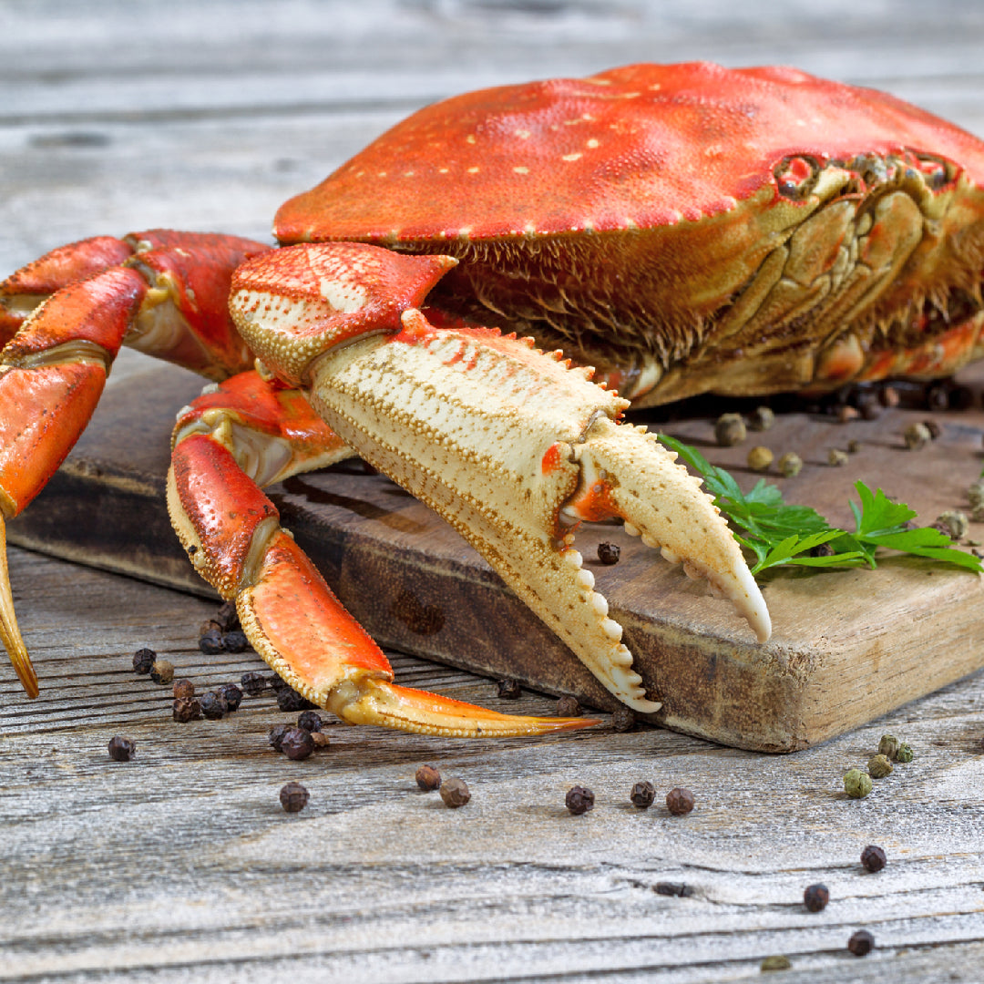 A spread of international crab claw dishes including chili crab, garlic butter crab claws, and crab bisque served on a rustic wooden table