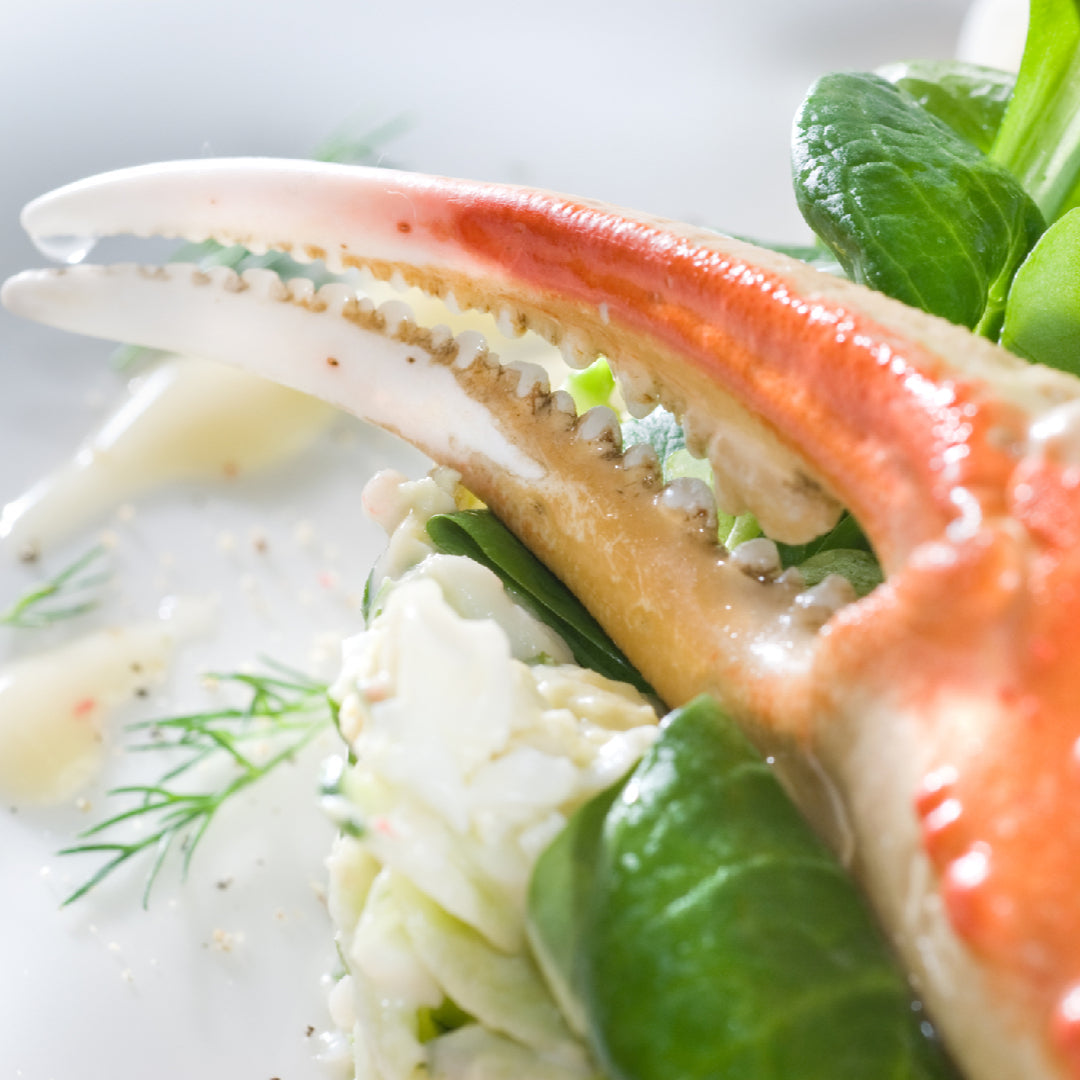 Fresh crab claws simmering in a golden garlic butter sauce in a cast iron skillet, garnished with parsley and lemon wedges
