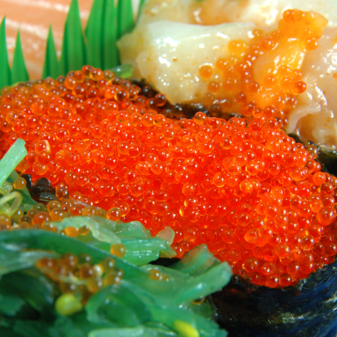 A plate of flying fish roe served on a bed of sushi rice with garnishes