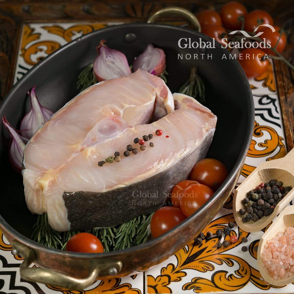 Pan-seared sturgeon steak with rosemary, tomatoes, and shallots in a skillet