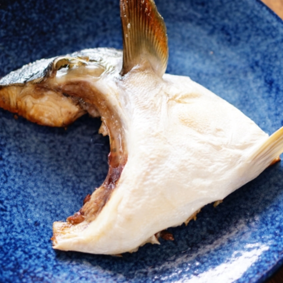 Golden crispy Hamachi fish tempura pieces served with dipping sauce, lemon wedges, and grated daikon on a Japanese ceramic plate