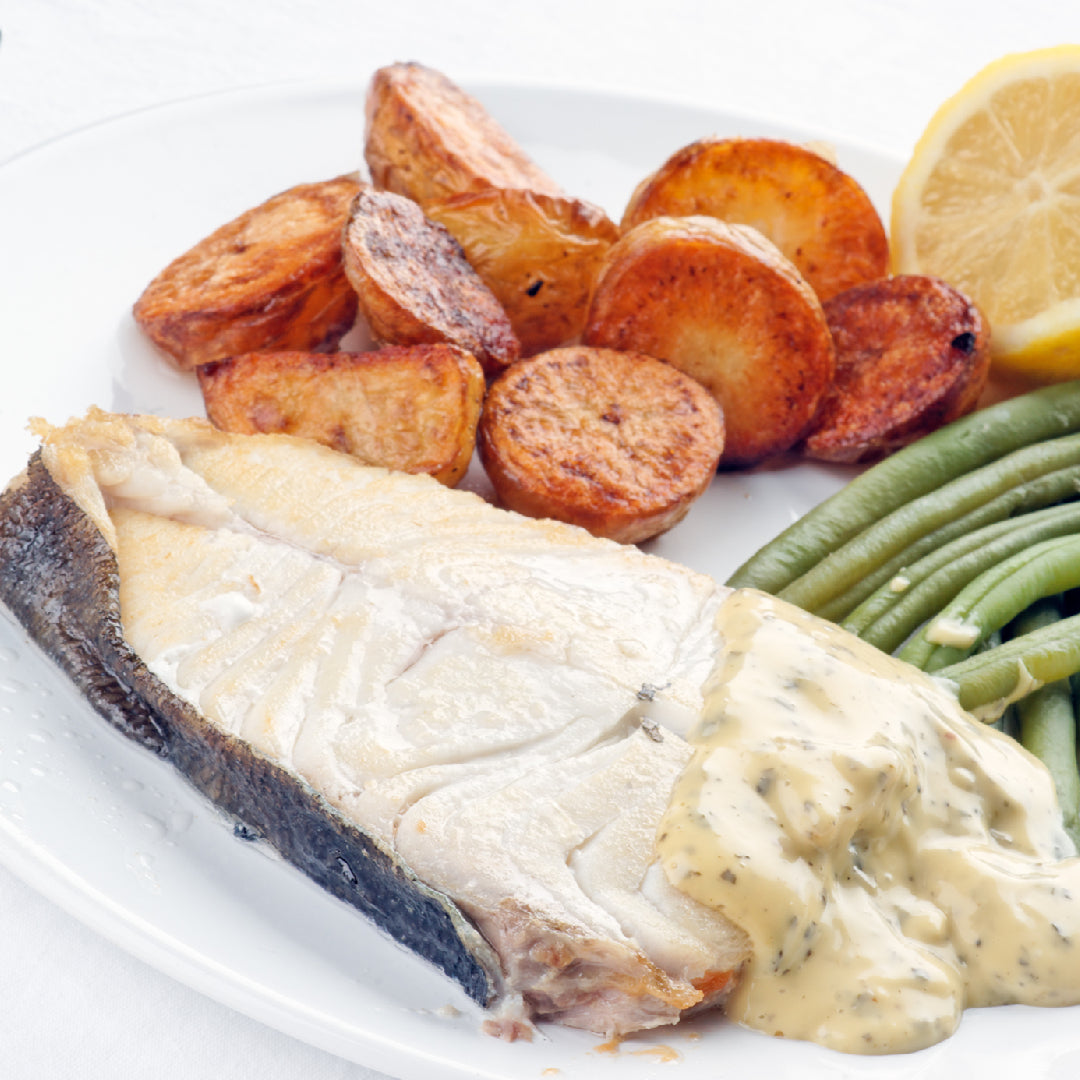 Fresh wild-caught halibut fillet on a plate with lemon and herbs, representing the nutritional benefits of halibut as a healthy seafood choice