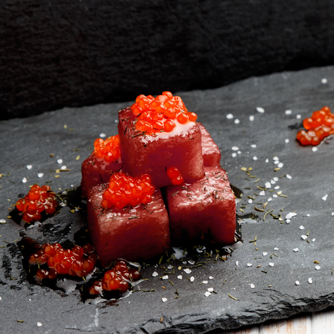 Glistening king salmon roe (ikura) in a small bowl showing its vibrant orange-red color and large egg size, served with a mother-of-pearl spoon
