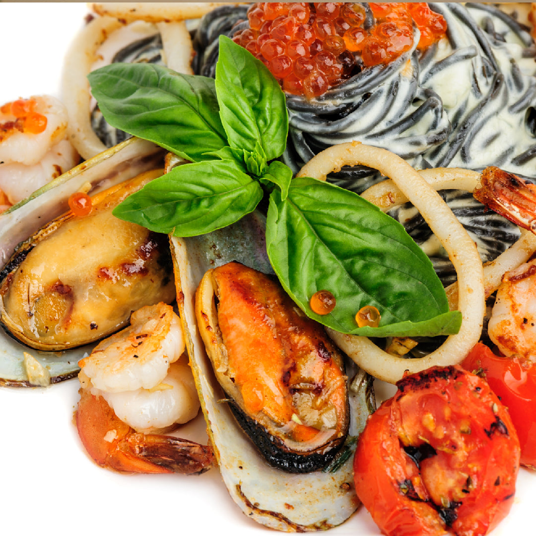 A photo of a plate of creamy Ikura Pasta with Parmesan cheese and fresh herbs on top.