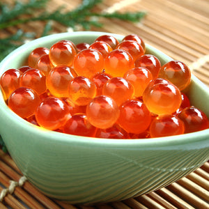 Bright, translucent salmon roe in a wooden bowl, epitomizing fresh Ikura's rich color and texture, set against a backdrop of sushi ingredients