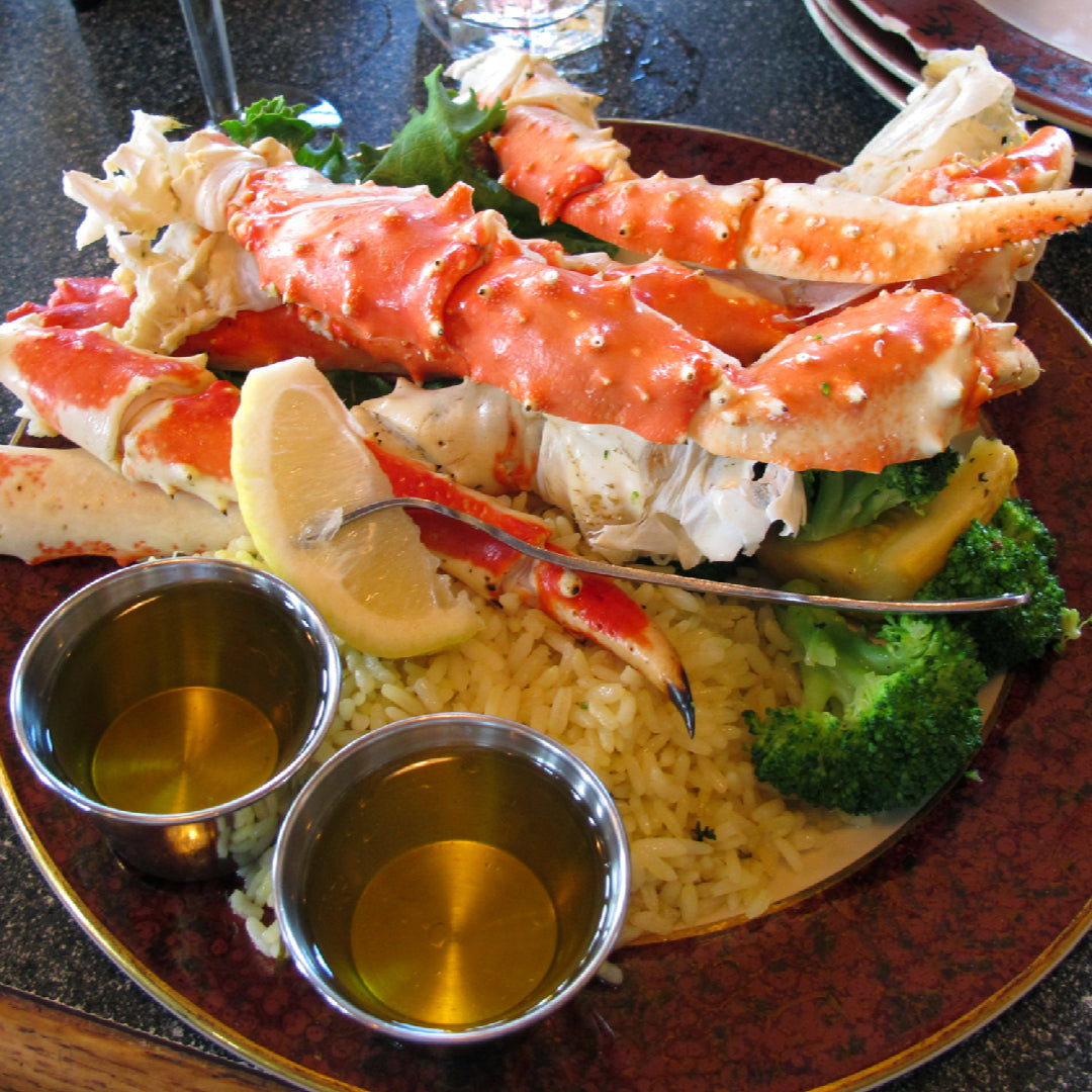 Creamy baked king crab legs dip served hot in a dish with crusty bread and crackers