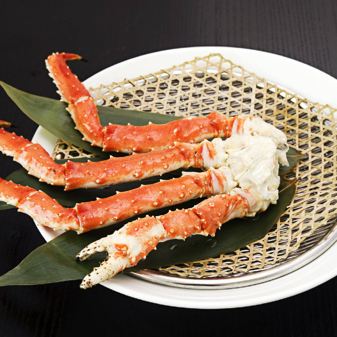 Perfectly baked king crab legs on a serving platter with garlic butter, lemon wedges, and fresh herbs