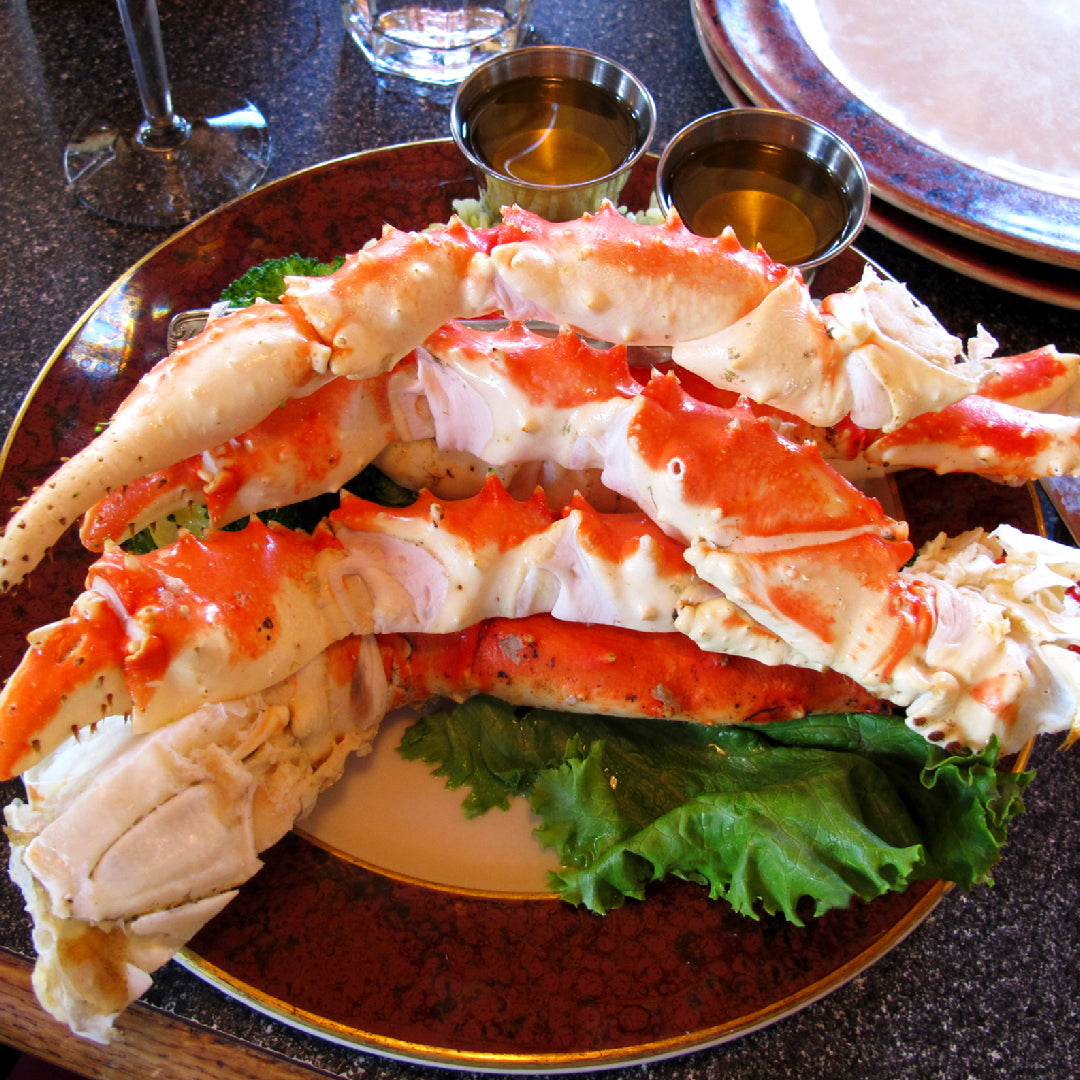 King crab legs with creamy pasta garnished with fresh parsley and lemon wedges