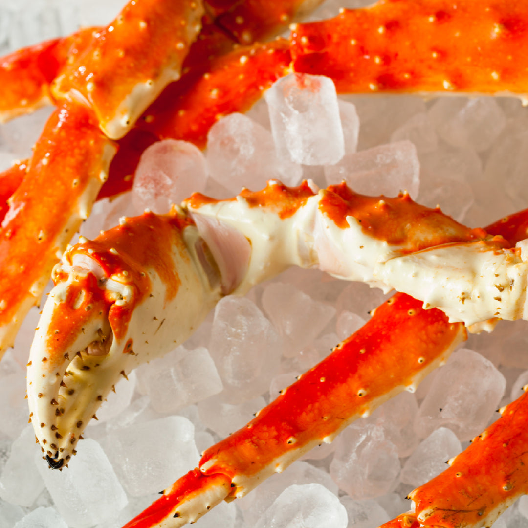 Jumbo Alaskan red king crab legs displayed on a seafood market counter with a price tag