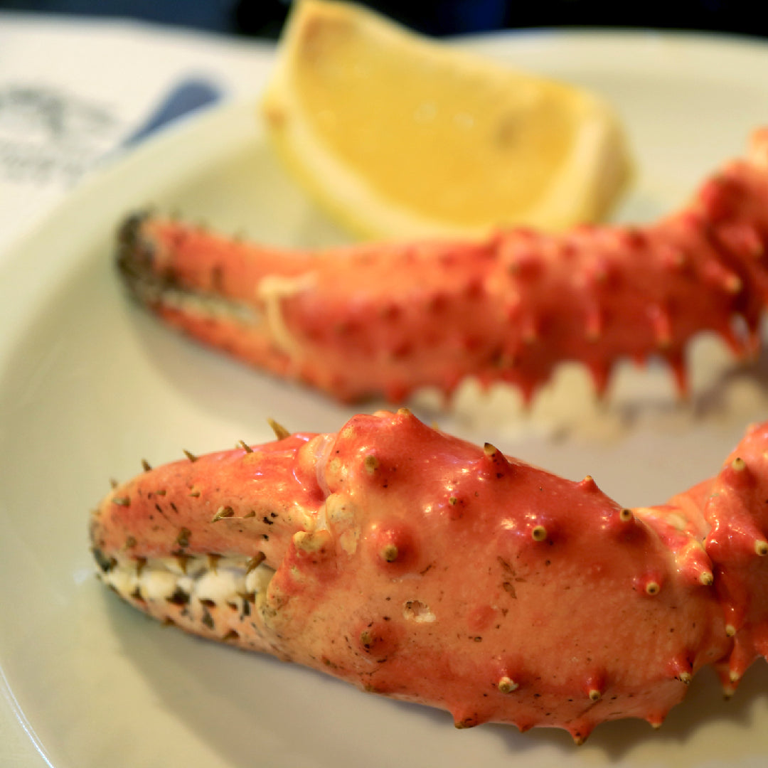 Fresh Alaskan king crab legs on ice with lemon wedges and melted butter dipping sauce