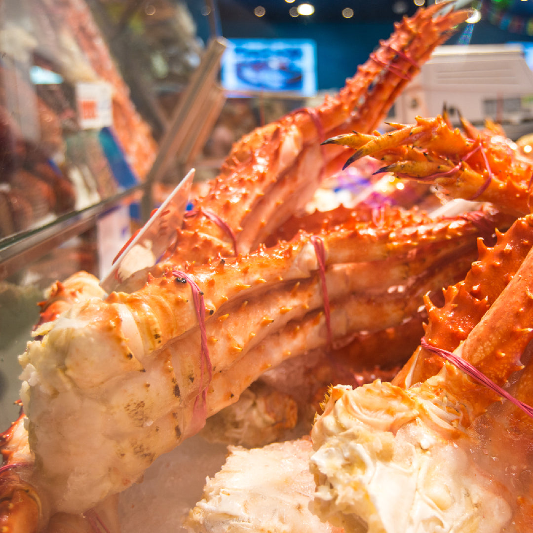 King crab legs being reheated in a steamer pot with melted butter on the side