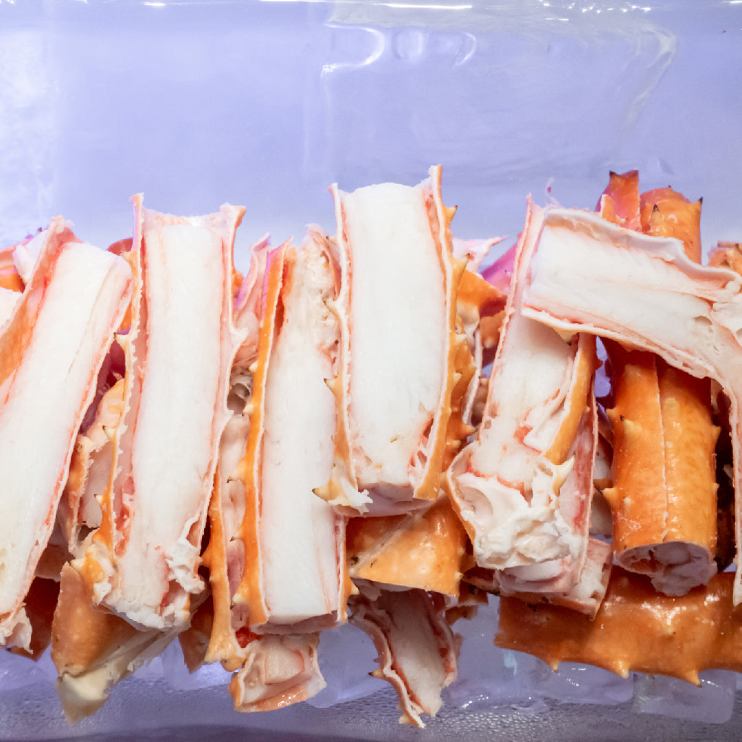 King crab legs grilling on a charcoal grill with butter baste and lemon