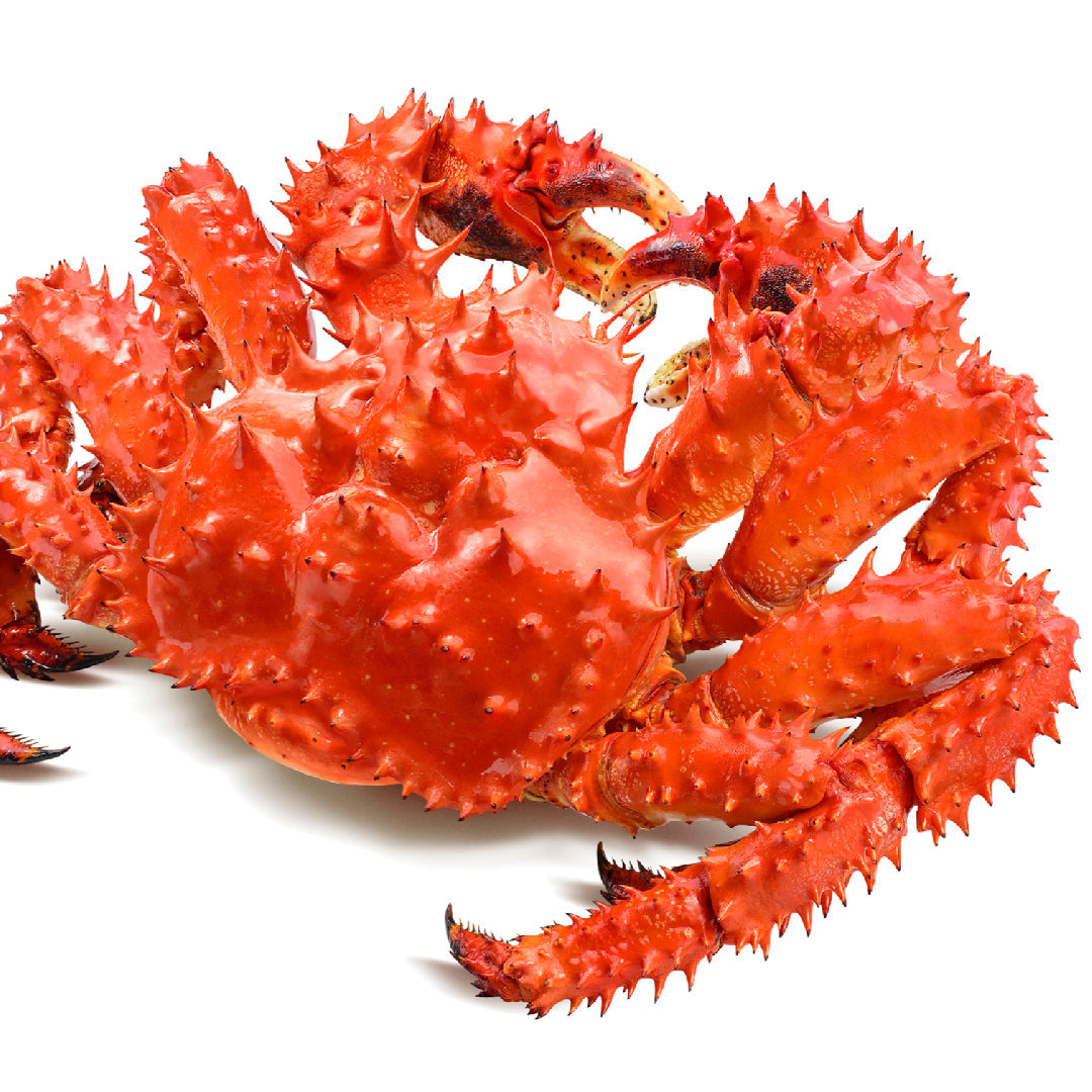 Alaskan red king crab legs on a wooden board with melted butter, lemon wedges, and fresh parsley, ready to serve
