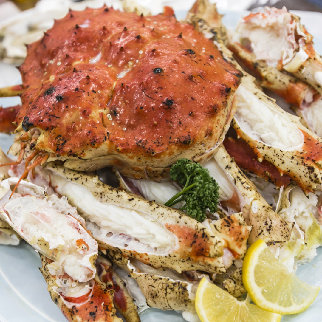 King crab legs on a serving platter with garlic butter and lemon wedges