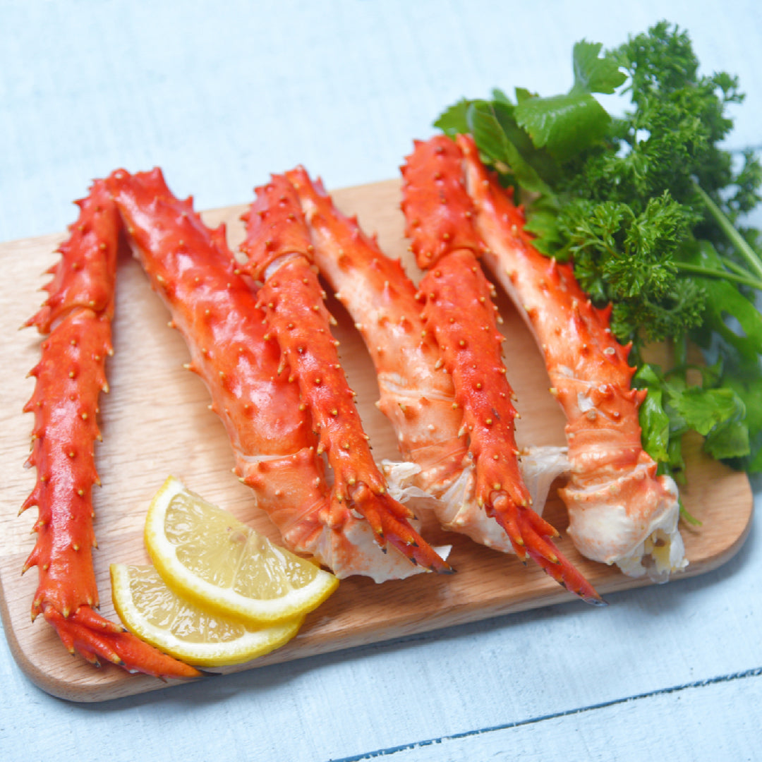 Side-by-side comparison of king crab legs and snow crab legs on a seafood platter with lemon and butter
