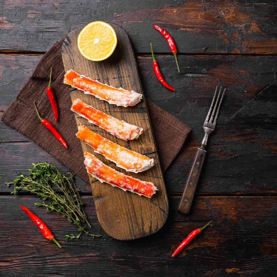 Snow crab leg being cracked with kitchen scissors along the length of the shell — the correct technique for extracting a clean, intact piece of snow crab meat without breaking it into pieces