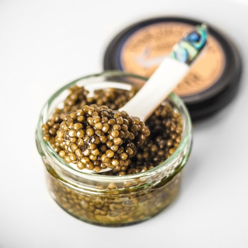 Malossol caviar served in a tin with mother-of-pearl spoon on a luxury table setting