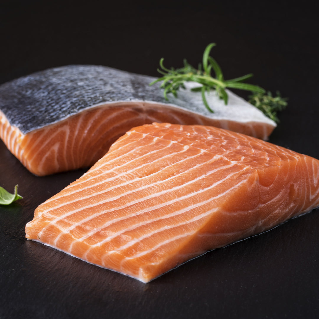 A glass of white wine alongside a beautifully plated Ora King Salmon fillet for a gourmet pairing