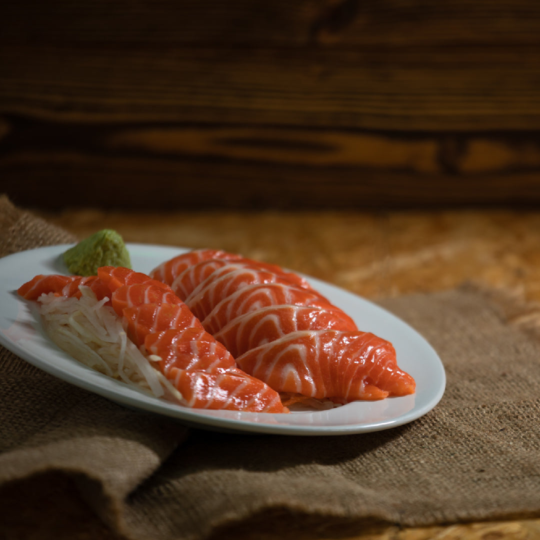 Fresh Ora King Salmon fillet showing rich marbling and vibrant orange color on a wooden board