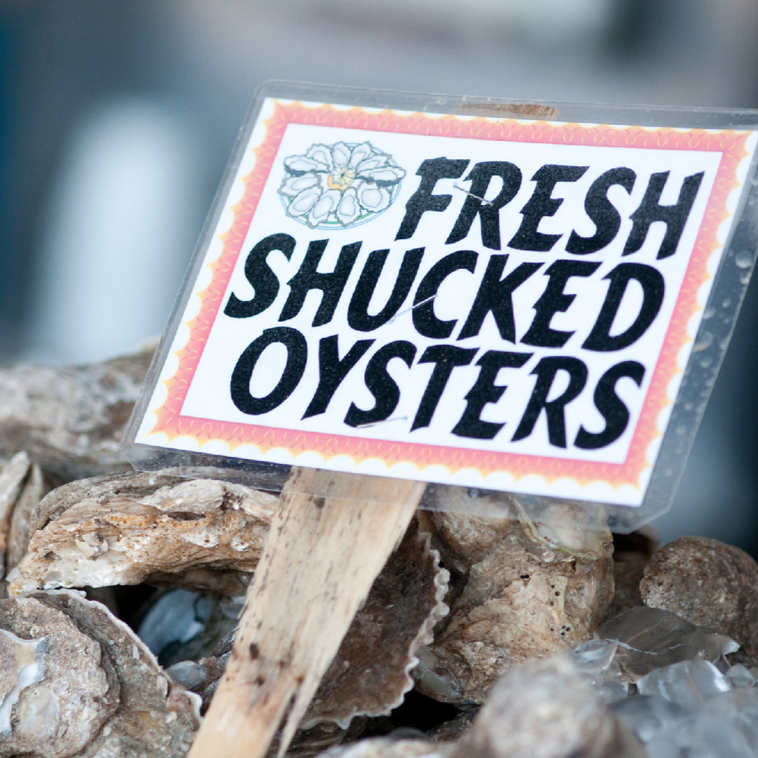 Fresh raw oysters on the half shell served on crushed ice with lemon wedges and mignonette sauce