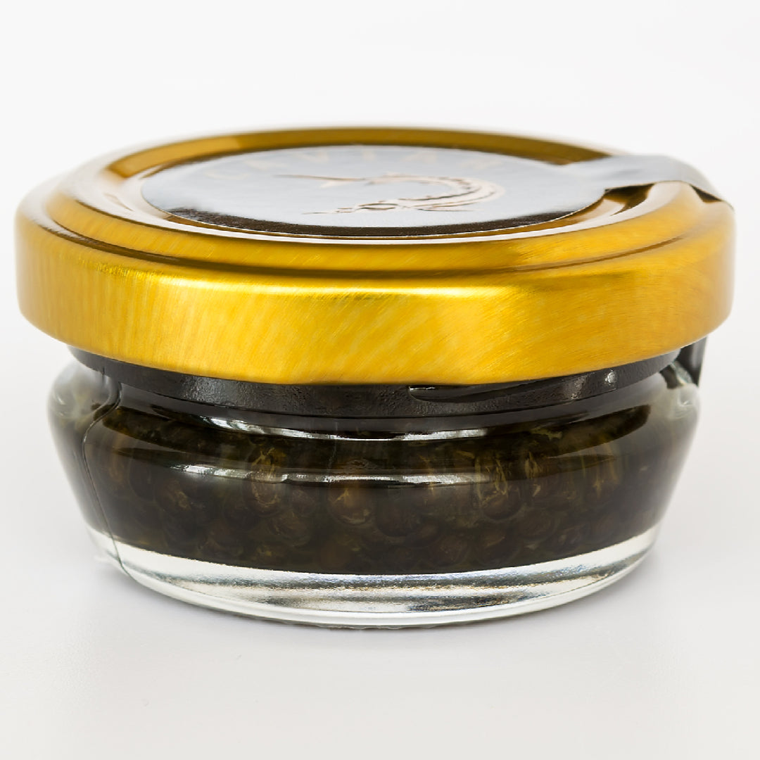 Three types of caviar in mother-of-pearl spoons side by side showing color and texture differences on a dark slate surface