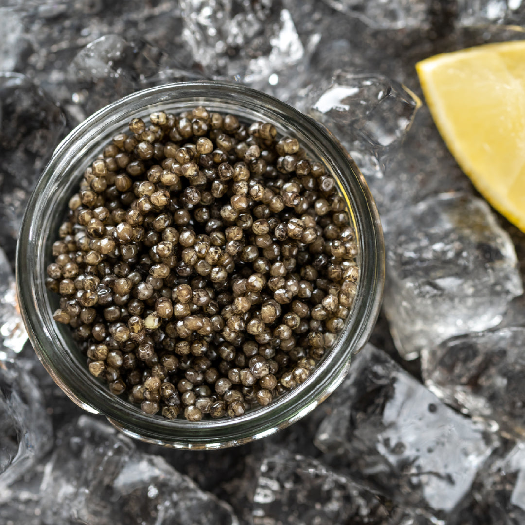 Assorted Osetra caviar varieties displayed side by side on crushed ice, showing the color range from golden amber to dark charcoal gray pearls