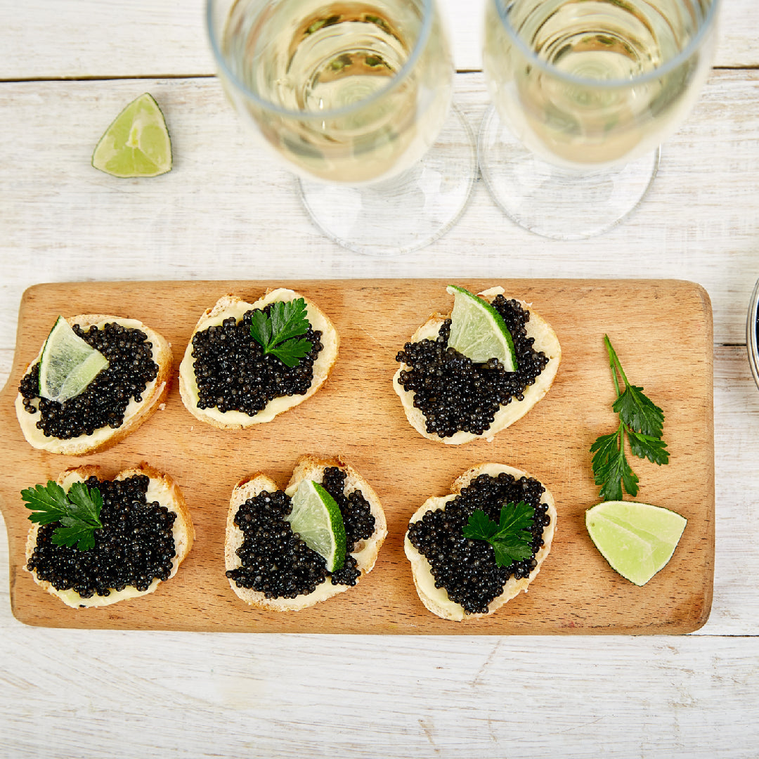 Assorted Osetra caviar appetizers including blinis, deviled eggs, and avocado toast arranged on a marble serving board
