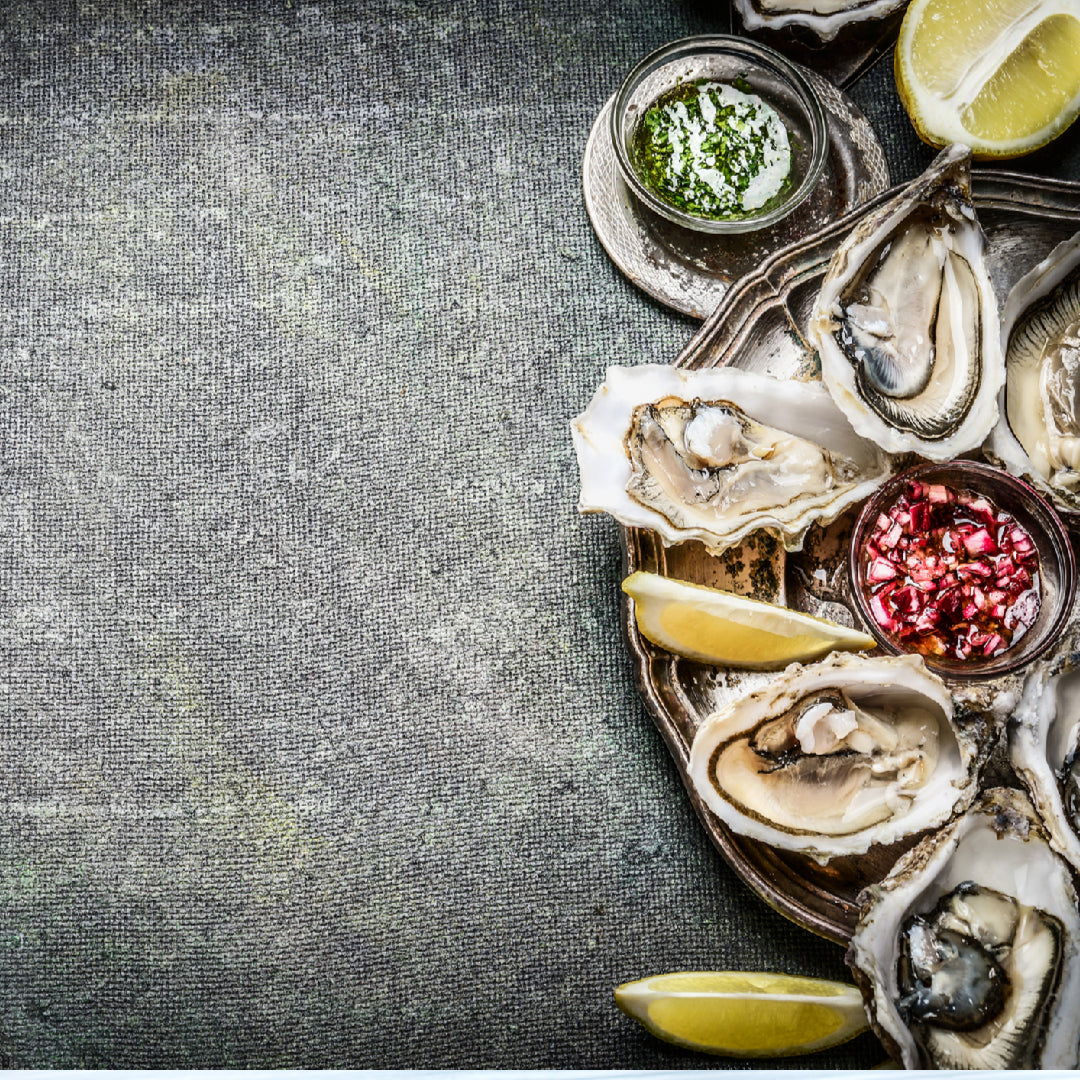 A bottle of oyster sauce beside fresh oysters and stir-fry vegetables on a kitchen counter