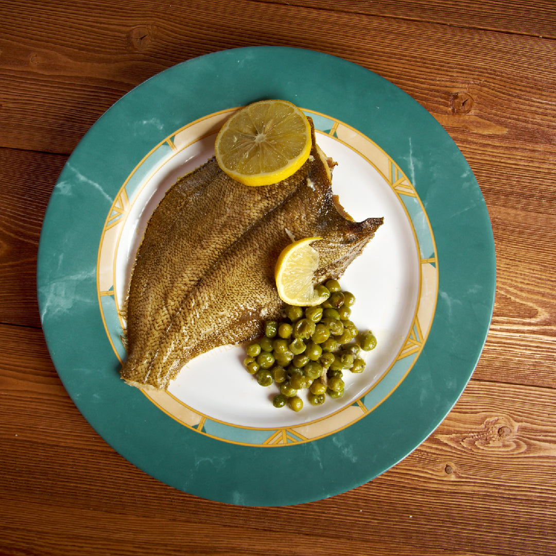 Grilled Petrale sole fillet with lemon slices and fresh herbs on a plate