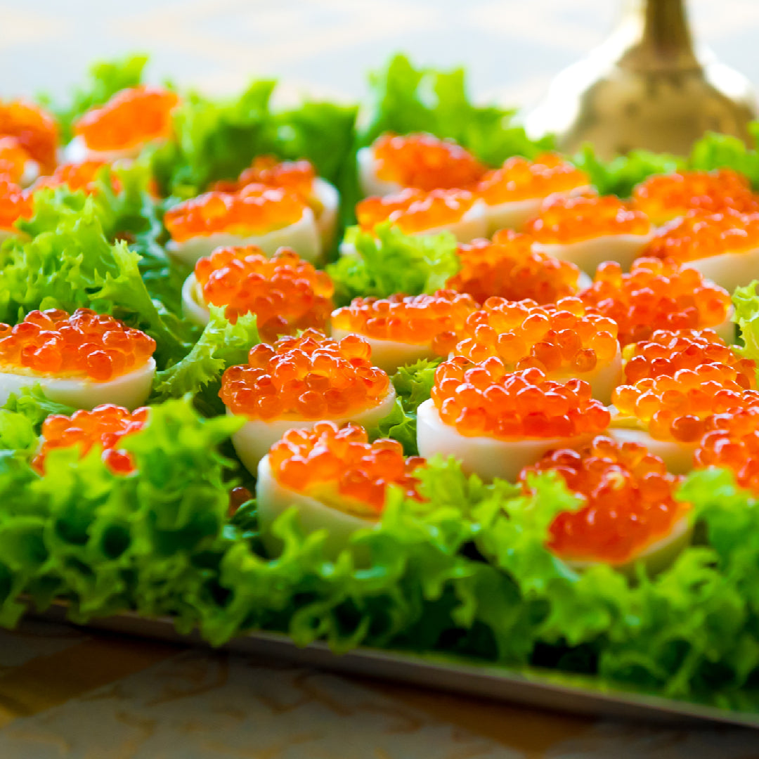 Pink caviar on a plate with crackers and lemon wedges