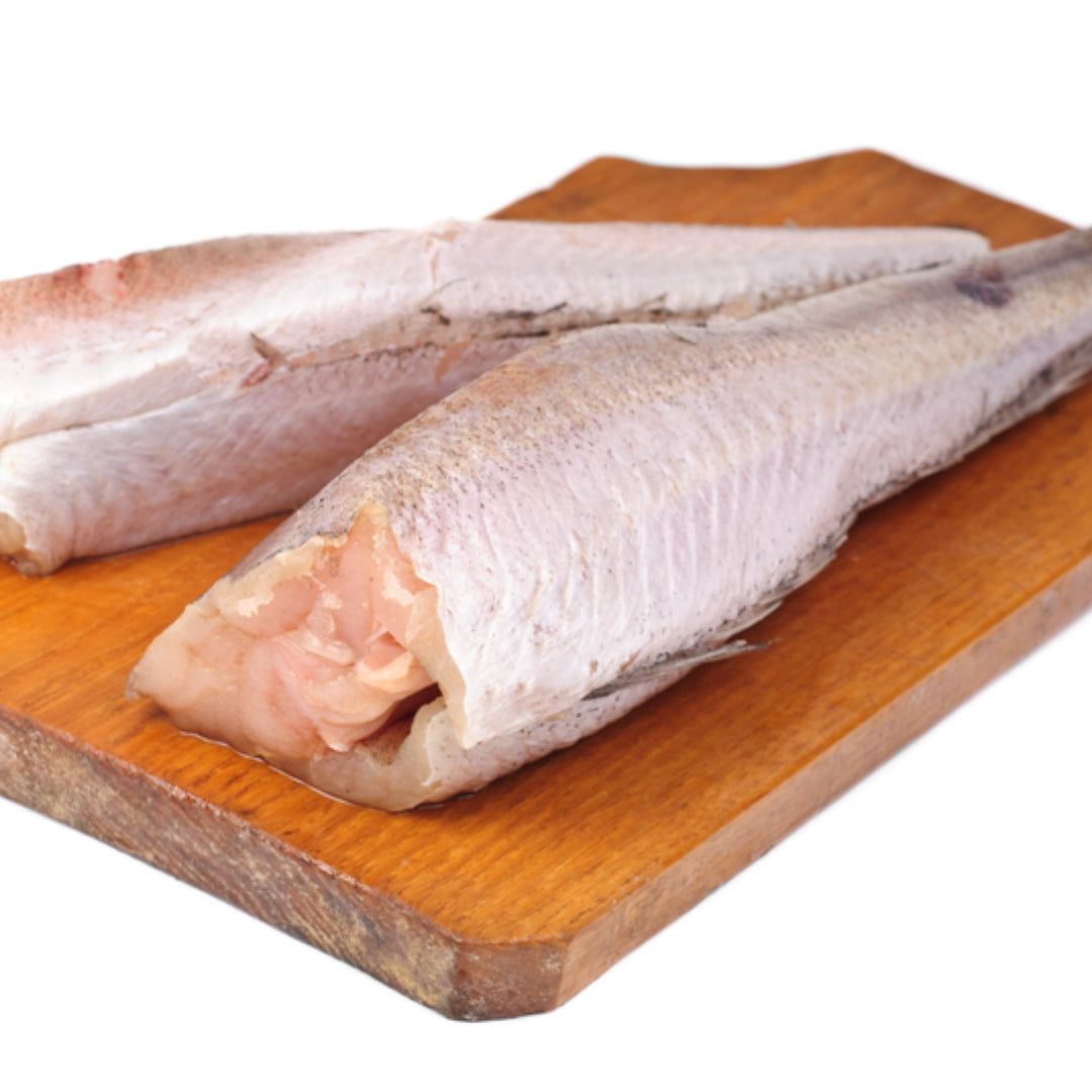 Fresh Alaskan pollock fillet on a plate with vegetables, lemon, and herbs showcasing its nutritional value
