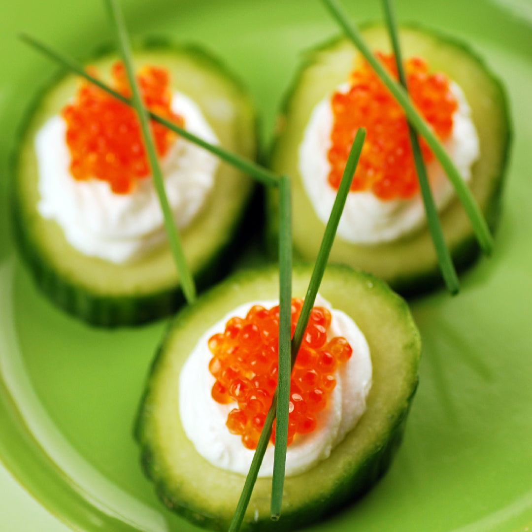 Salmon roe served on blinis with crème fraîche alongside a traditional sake set with ochoko cups on a Japanese-inspired table setting