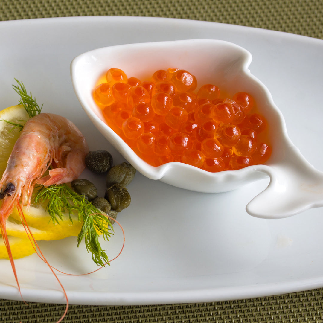 Five gourmet salmon roe dishes including sushi, crostini, avocado salad, pasta, and scrambled eggs displayed on an elegant table