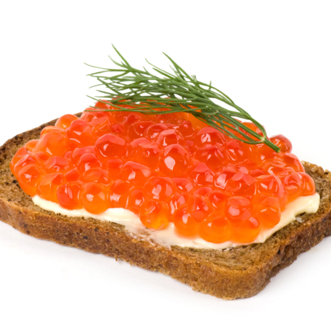 Bright orange ikura salmon roe pearls served in a ceramic bowl over sushi rice, garnished with nori strips and sesame seeds on a wooden board